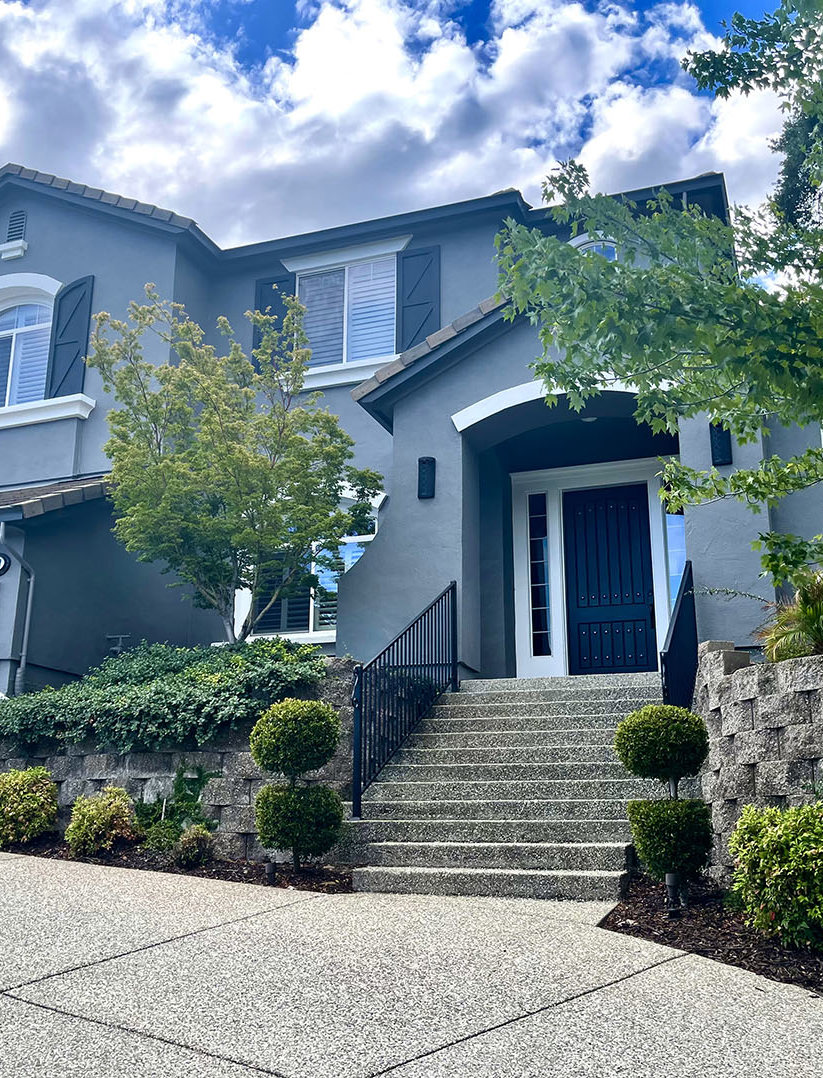 Light gray home with dark trim, stone steps and landscaping